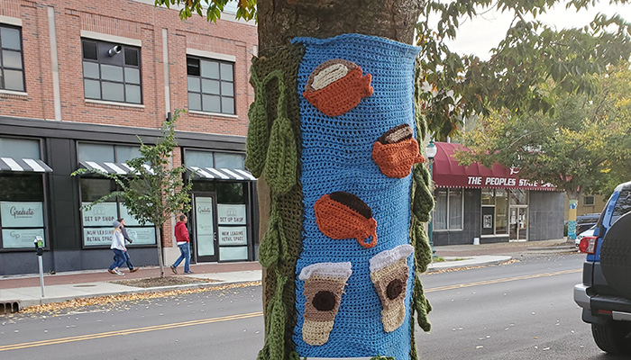 city street with tree decorated with yarn art